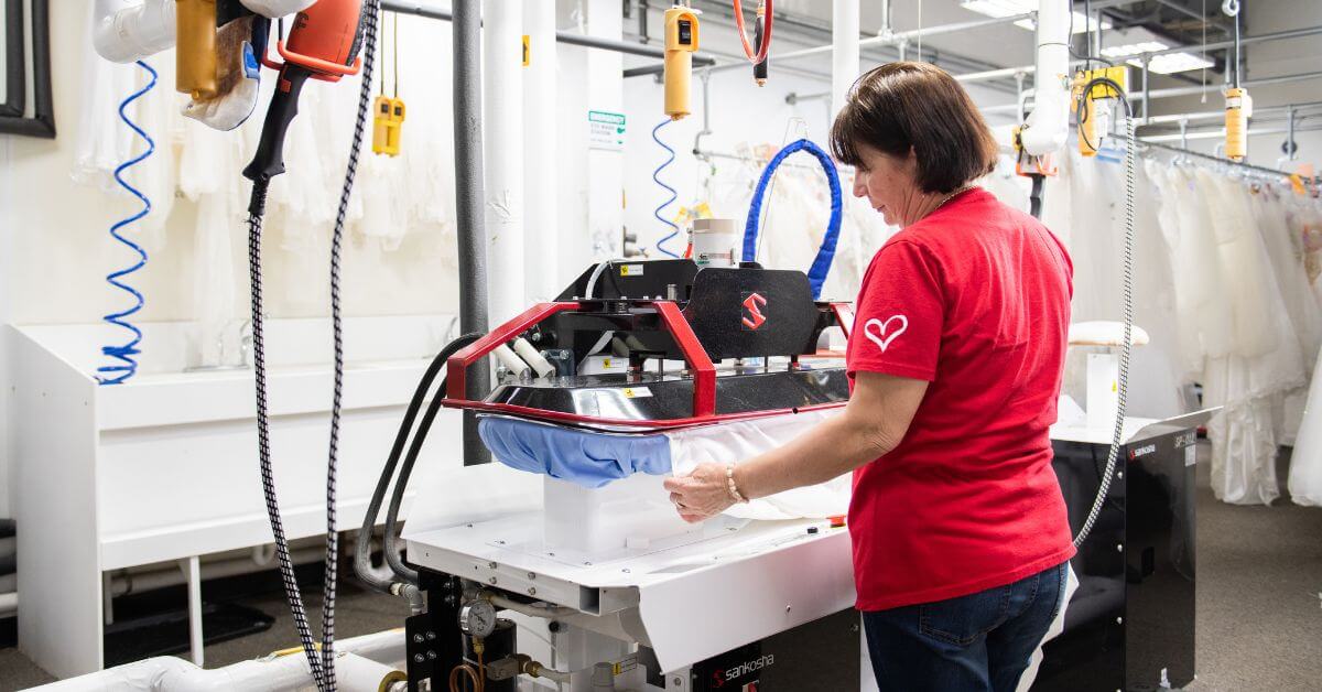 A professional garment specialist working on a wedding dress preservation process in a modern facility.